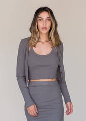 Woman wearing a gray ribbed top and skirt set against a plain background