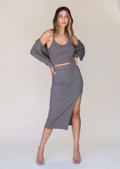 Woman wearing a gray outfit with a top and skirt against a plain background