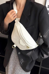 Person wearing a black blazer and gray pants with a white crossbody bag.