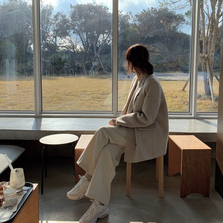 Person sitting in a modern cafe looking out large windows at a park.