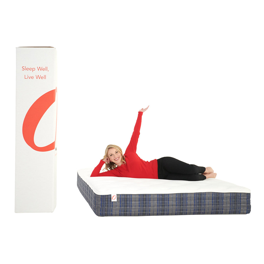 Person lying on a mattress with a large branded box next to it on a white background