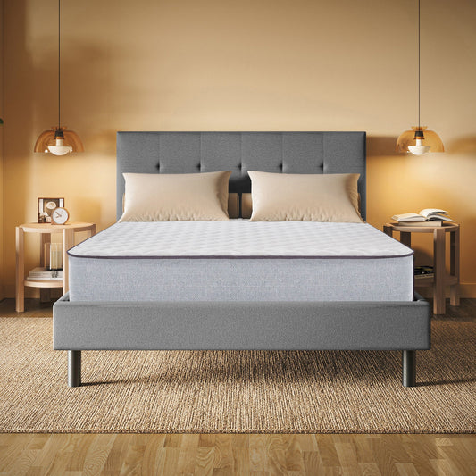 Gray upholstered bed with a mattress in a bedroom setting.