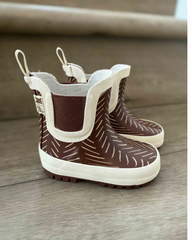 Pair of brown and white children's rain boots on a wooden surface.