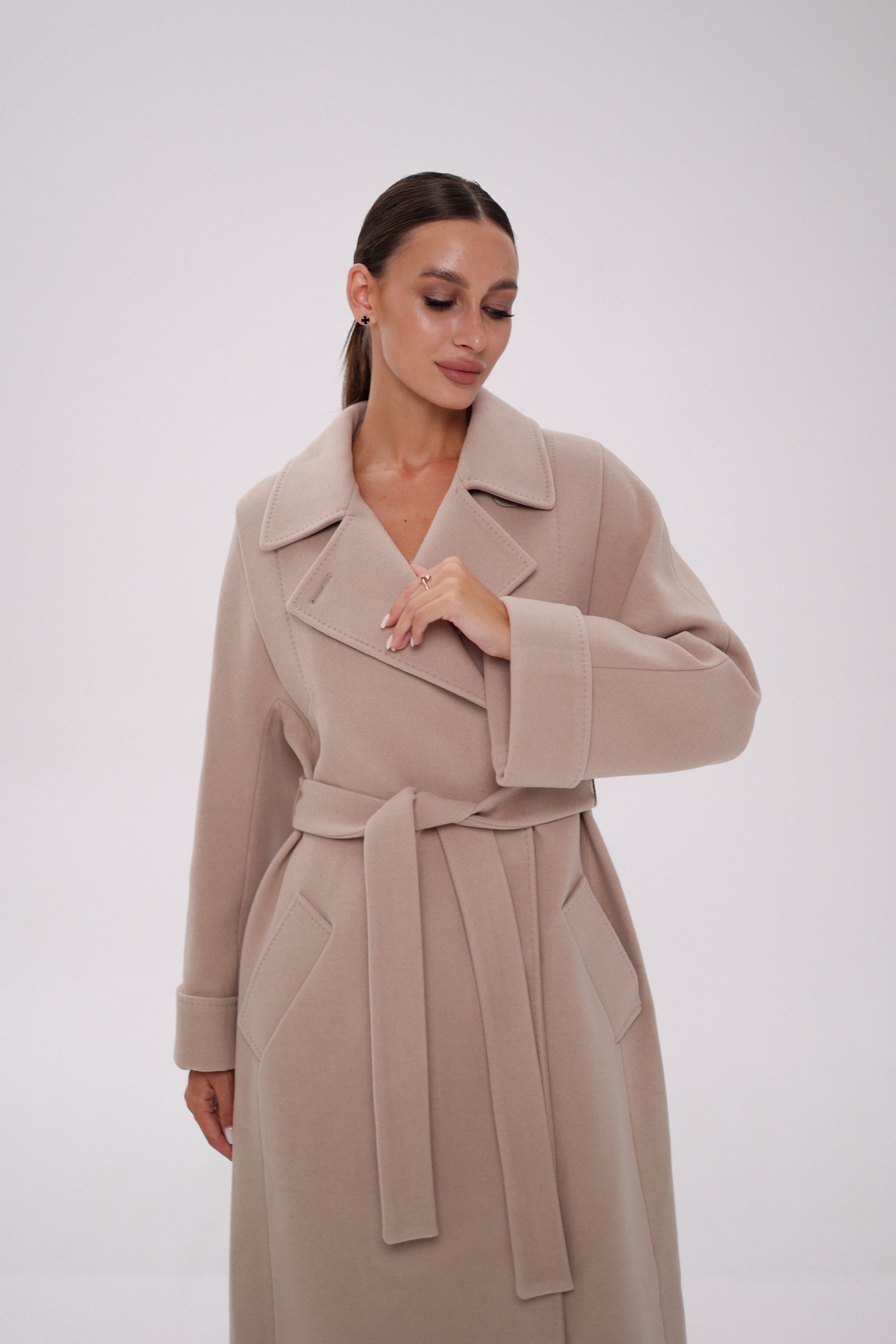 Woman wearing a beige trench coat on a white background