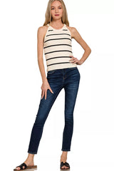 Woman wearing a striped tank top and blue jeans on a white background
