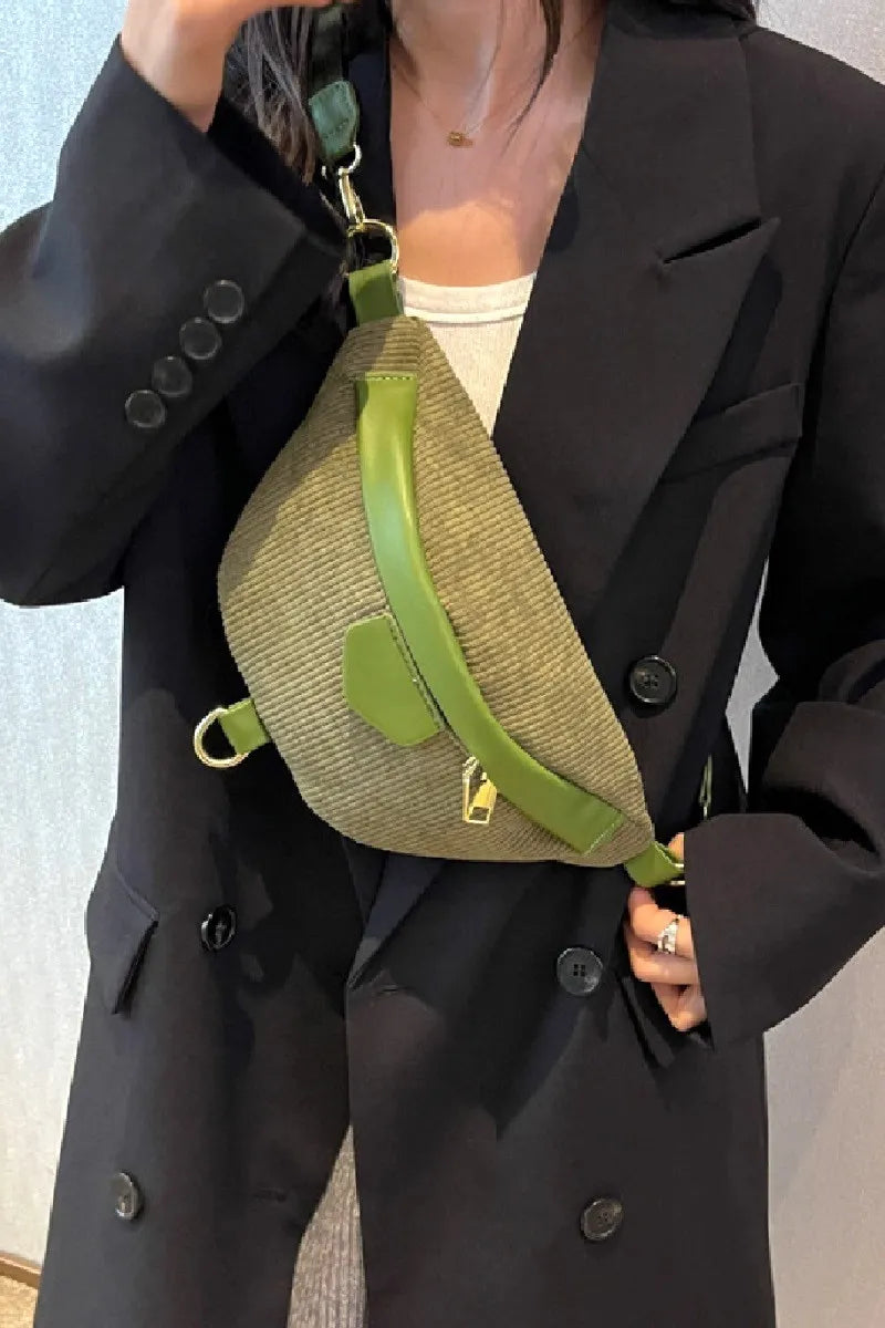 Person wearing a black coat holding a green and beige bag.