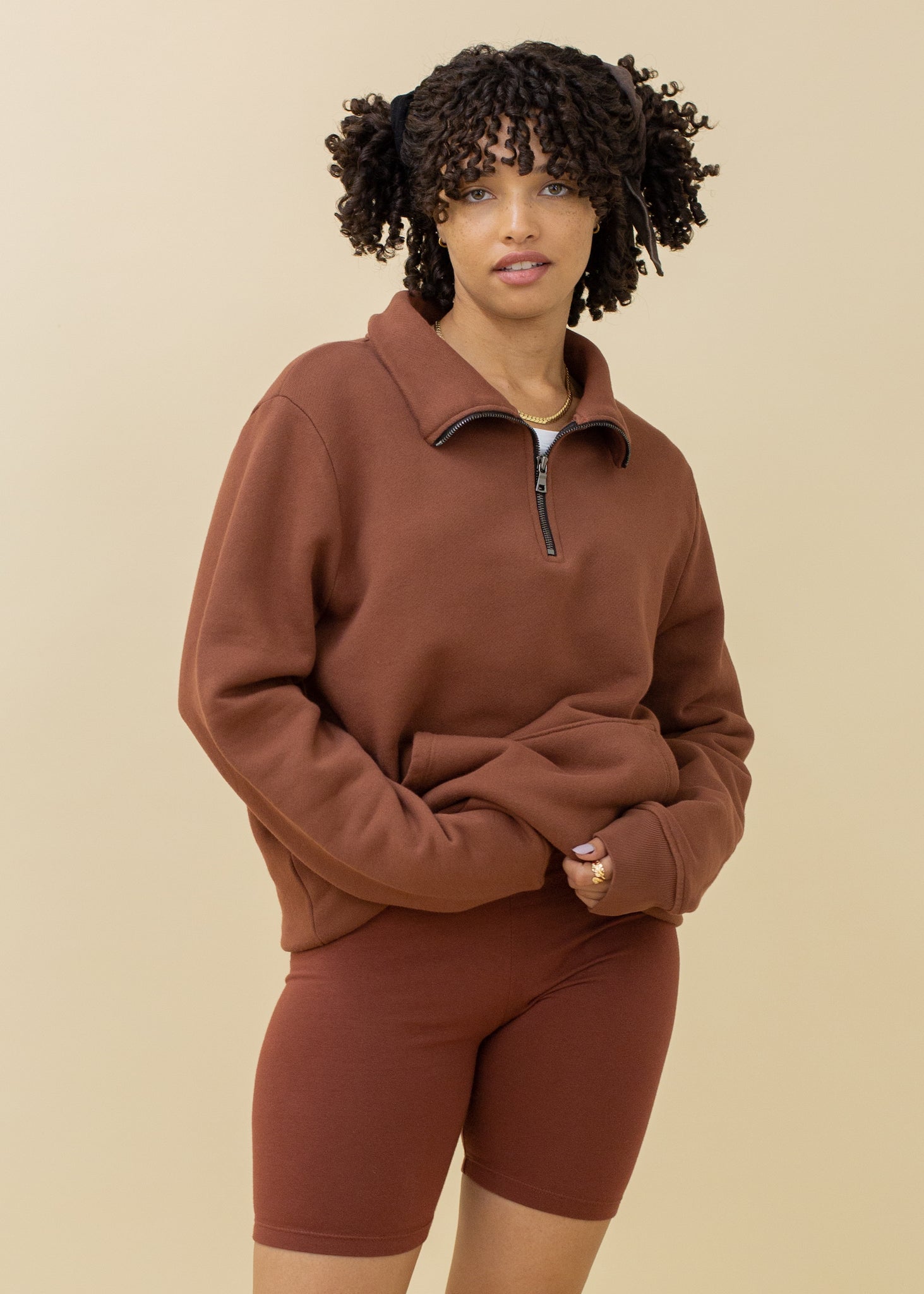 Woman wearing a brown sweatshirt and shorts on a beige background