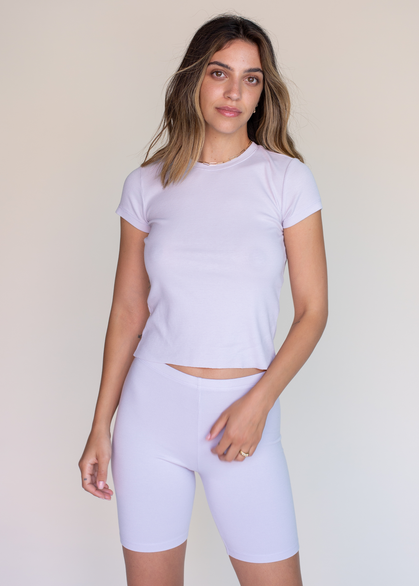 Woman wearing a light purple athletic outfit on a plain background