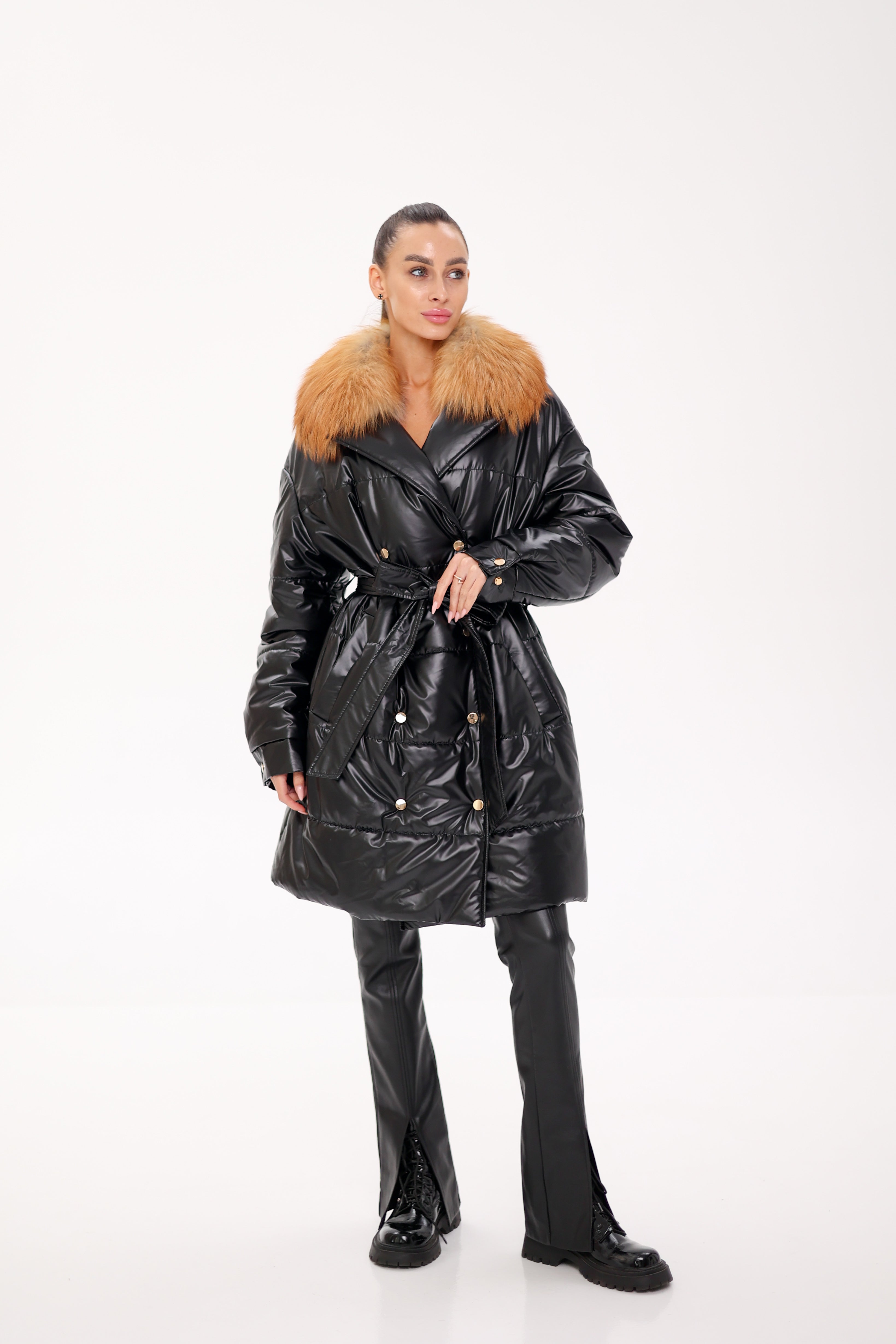 Person wearing a black puffer coat with a fur collar on a white background