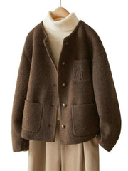 A chestnut brown reversible woolen coat with embroidery on the chest area, displayed on a mannequin wearing a white turtleneck sweater and a beige skirt.