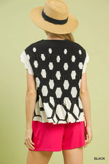 Person wearing a black and white patterned top with pink shorts and a straw hat on a light green background.