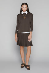 Woman wearing a brown dress with a white collar against a gray background