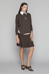 Woman wearing a brown dress with a white collar against a gray background