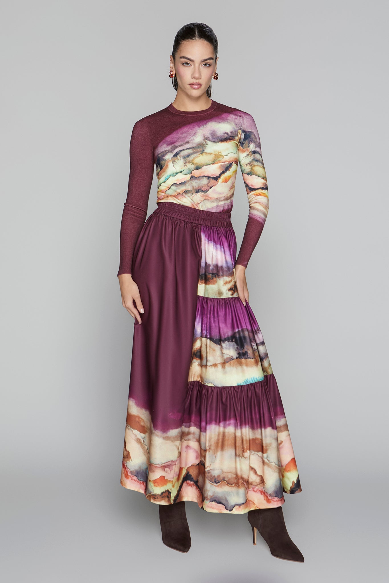 Woman wearing a long, burgundy dress with a colorful abstract pattern on a gray background