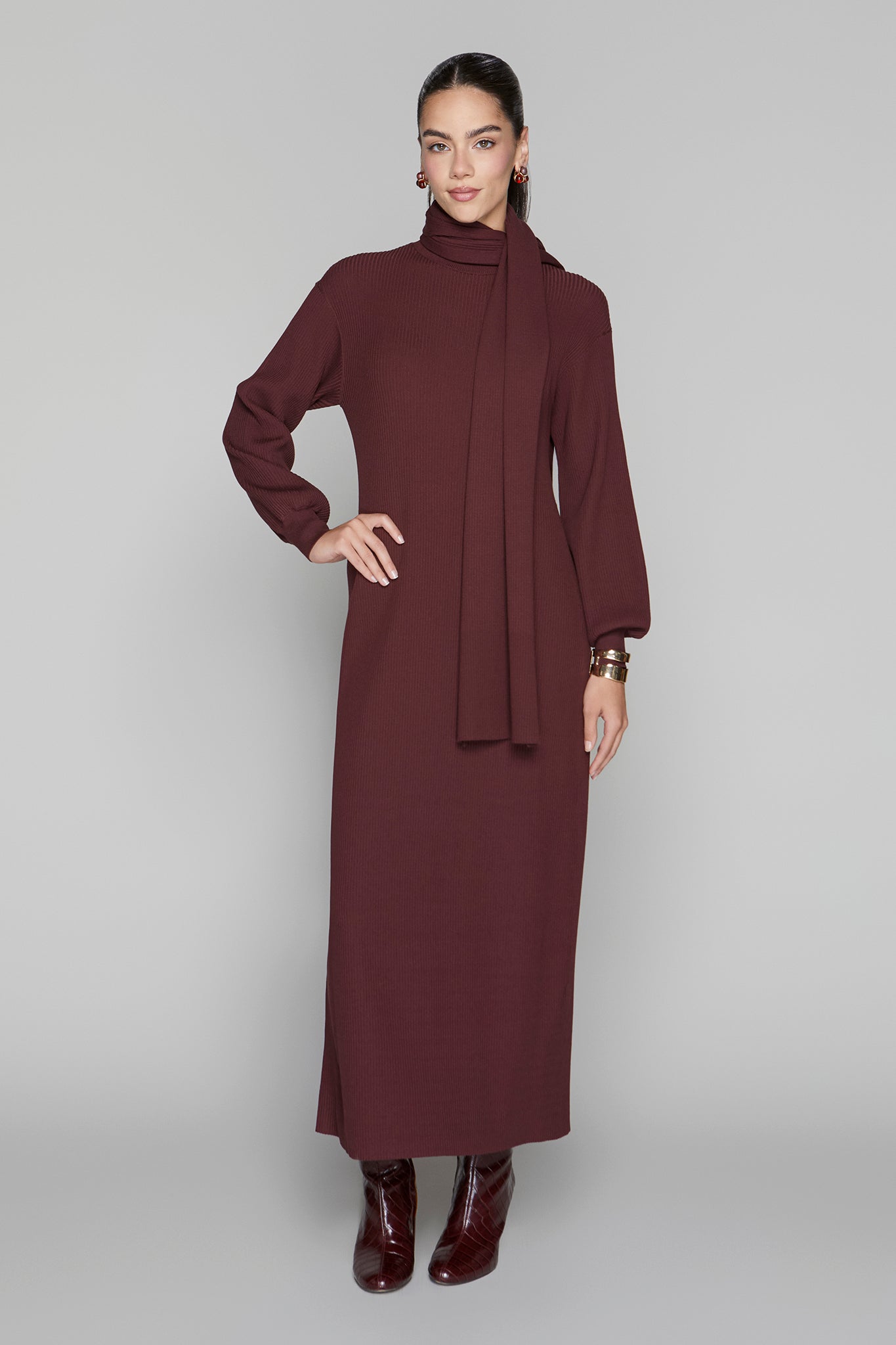 Woman wearing a long burgundy dress against a gray background