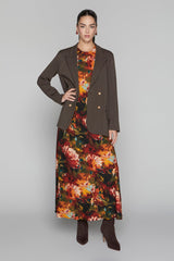 Woman wearing a brown coat over a floral dress on a gray background