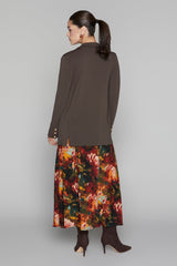 Woman wearing a brown long-sleeve top and a colorful floral skirt on a gray background