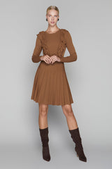 Woman wearing a brown dress with ruffled sleeves and matching boots on a gray background