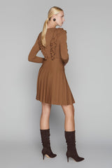 Woman wearing a brown dress with ruffled details and matching knee-high boots on a gray background