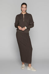 Woman wearing a brown outfit with a long skirt on a gray background