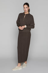 Woman wearing a brown outfit with a long skirt on a gray background