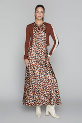 Woman wearing a patterned dress with a brown cardigan on a gray background