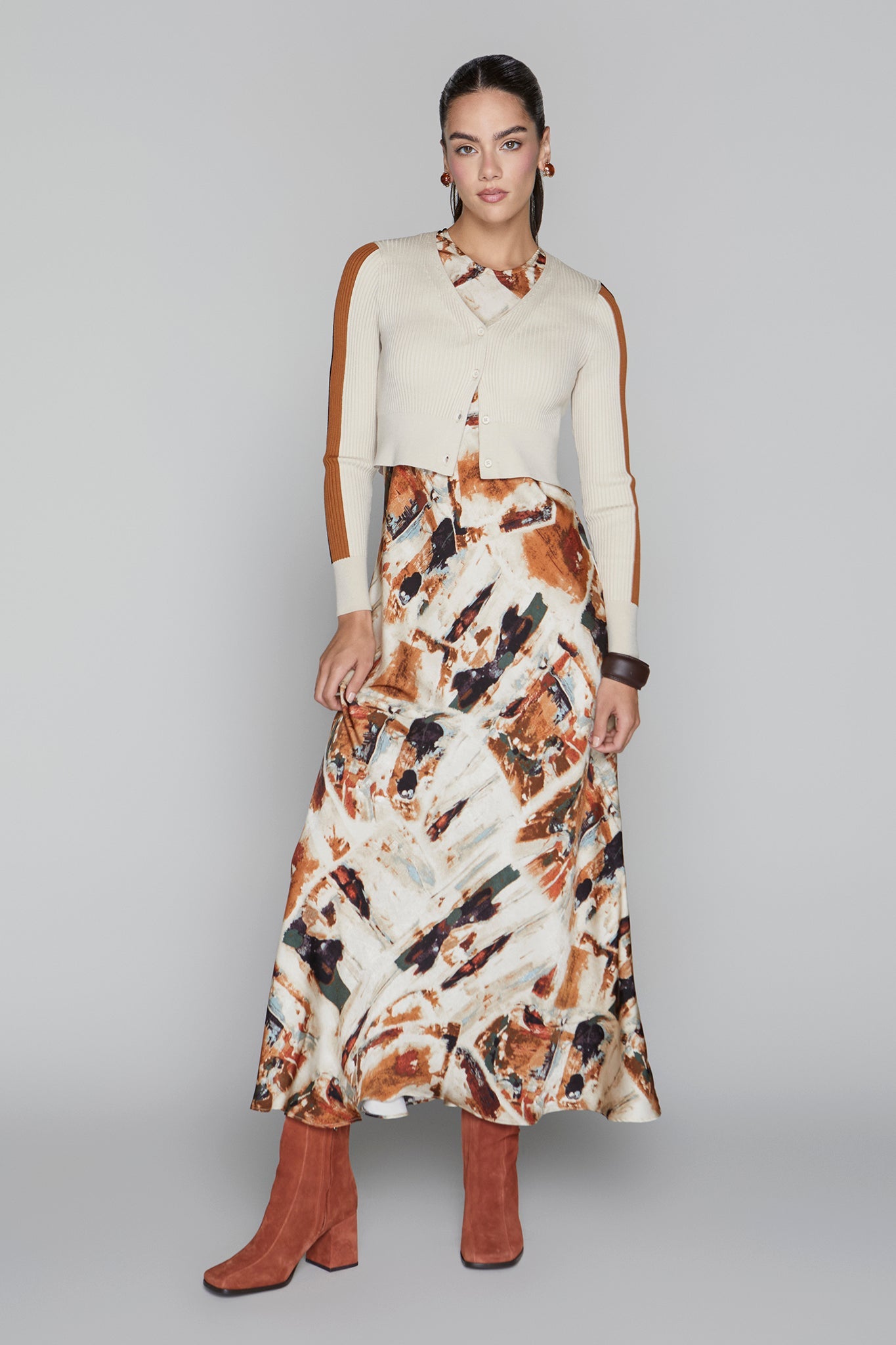 Woman wearing a cream sweater and patterned skirt on a gray background