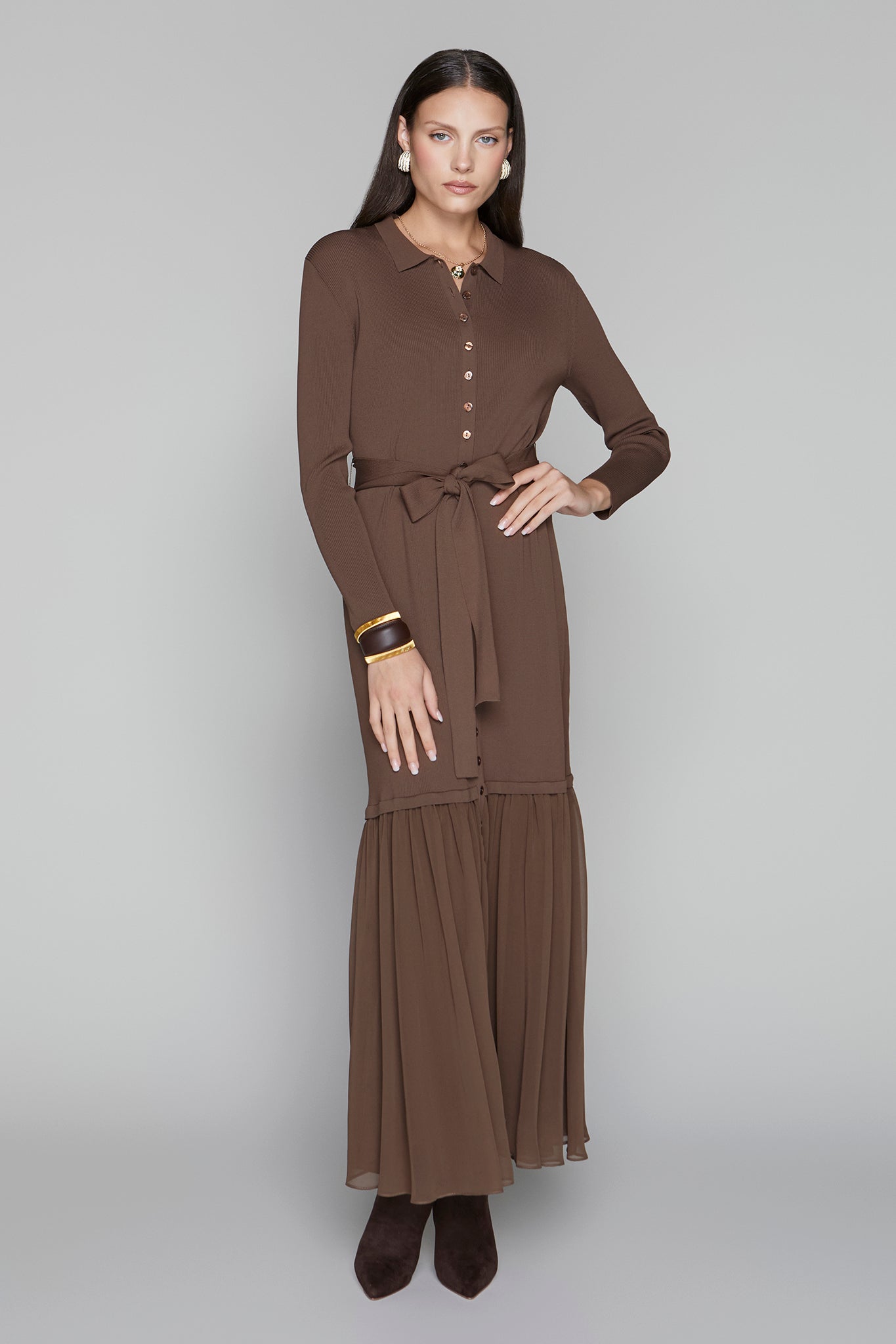 Woman wearing a brown dress with a belt on a gray background