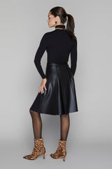 Woman wearing a black leather skirt and leopard print boots on a gray background