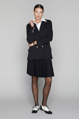 Woman wearing a black suit with a white shirt on a gray background