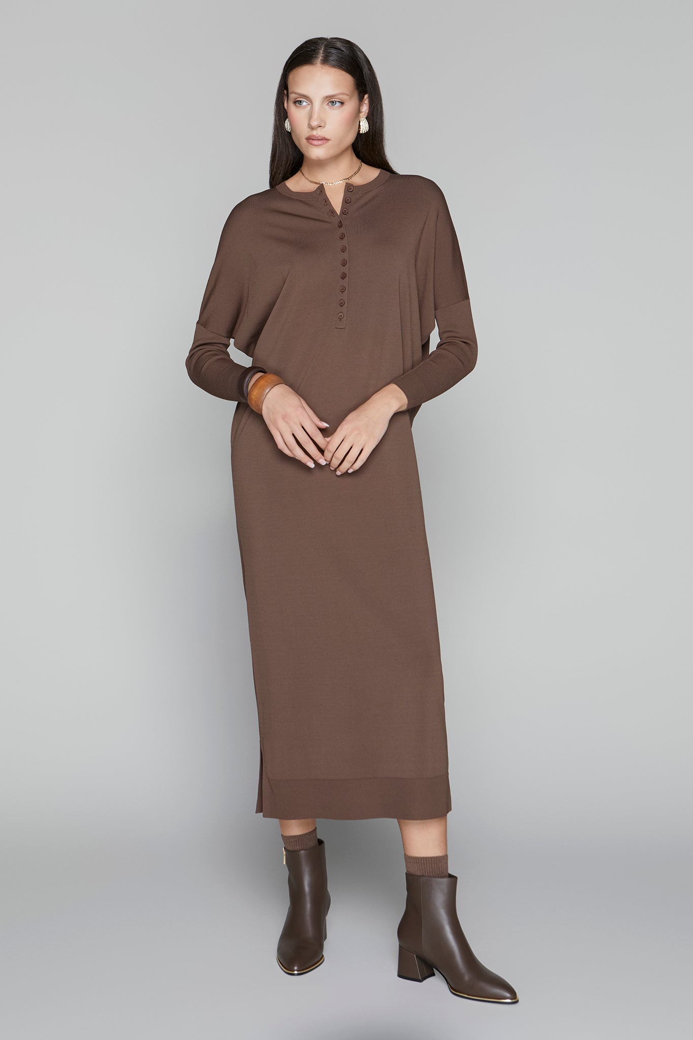 Woman wearing a brown dress with long sleeves on a gray background
