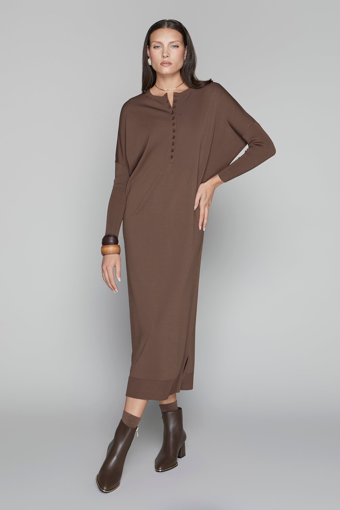 Woman wearing a brown dress with long sleeves on a gray background