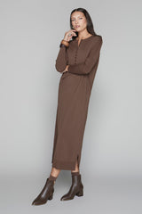 Woman wearing a brown dress and boots on a gray background