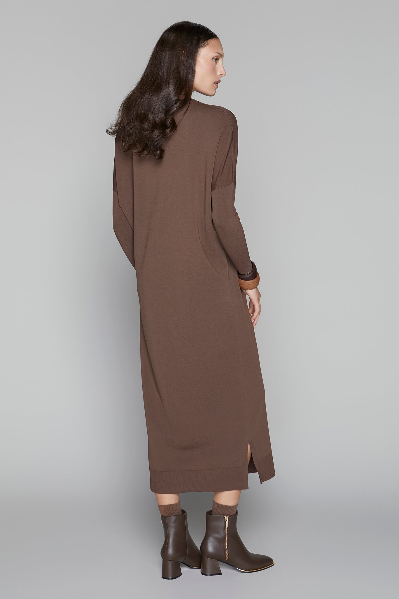 Woman wearing a long brown dress on a gray background