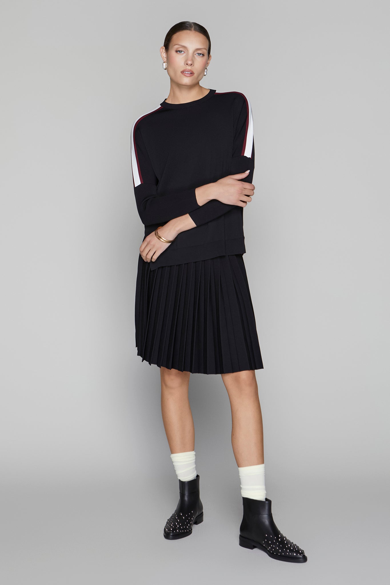 Woman wearing a black outfit with white accents on a gray background