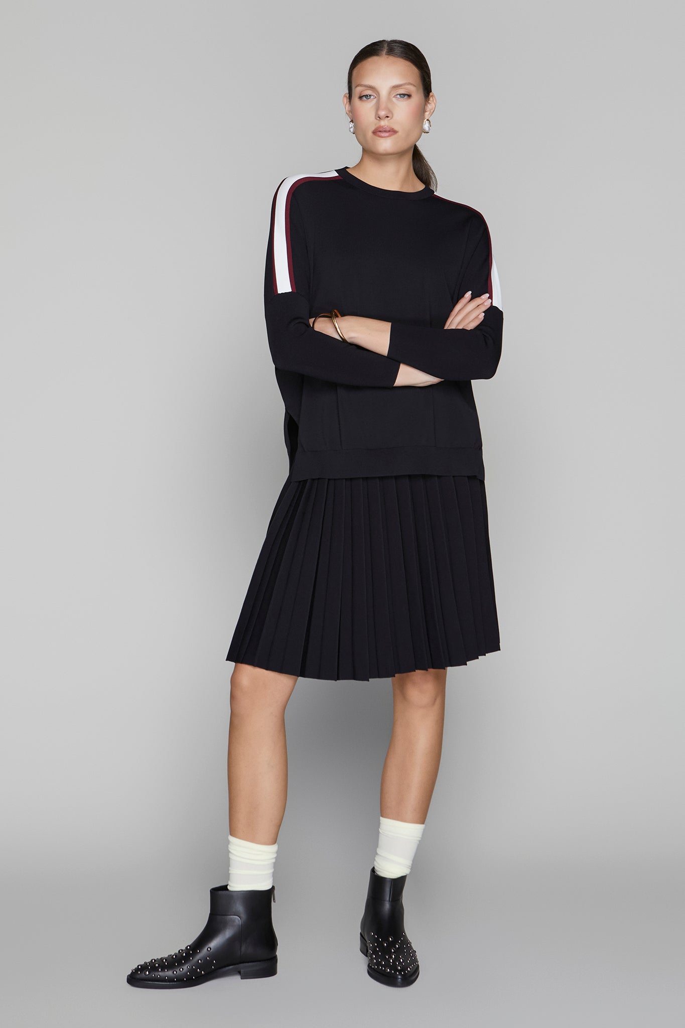 Woman wearing a black outfit with white accents on a gray background