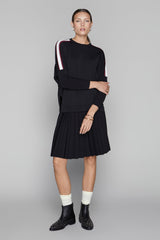 Woman wearing a black outfit with white accents on a gray background