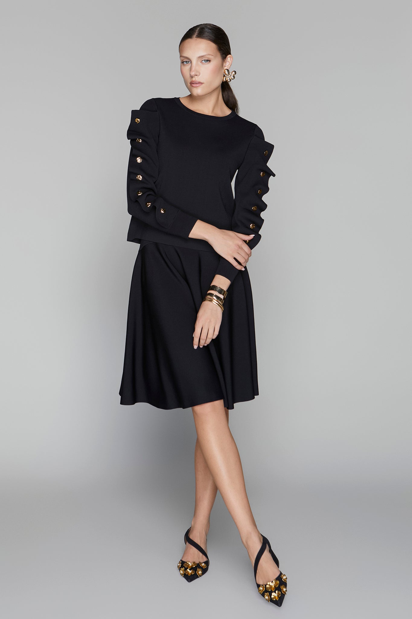 Woman wearing a black dress with decorative sleeves on a gray background