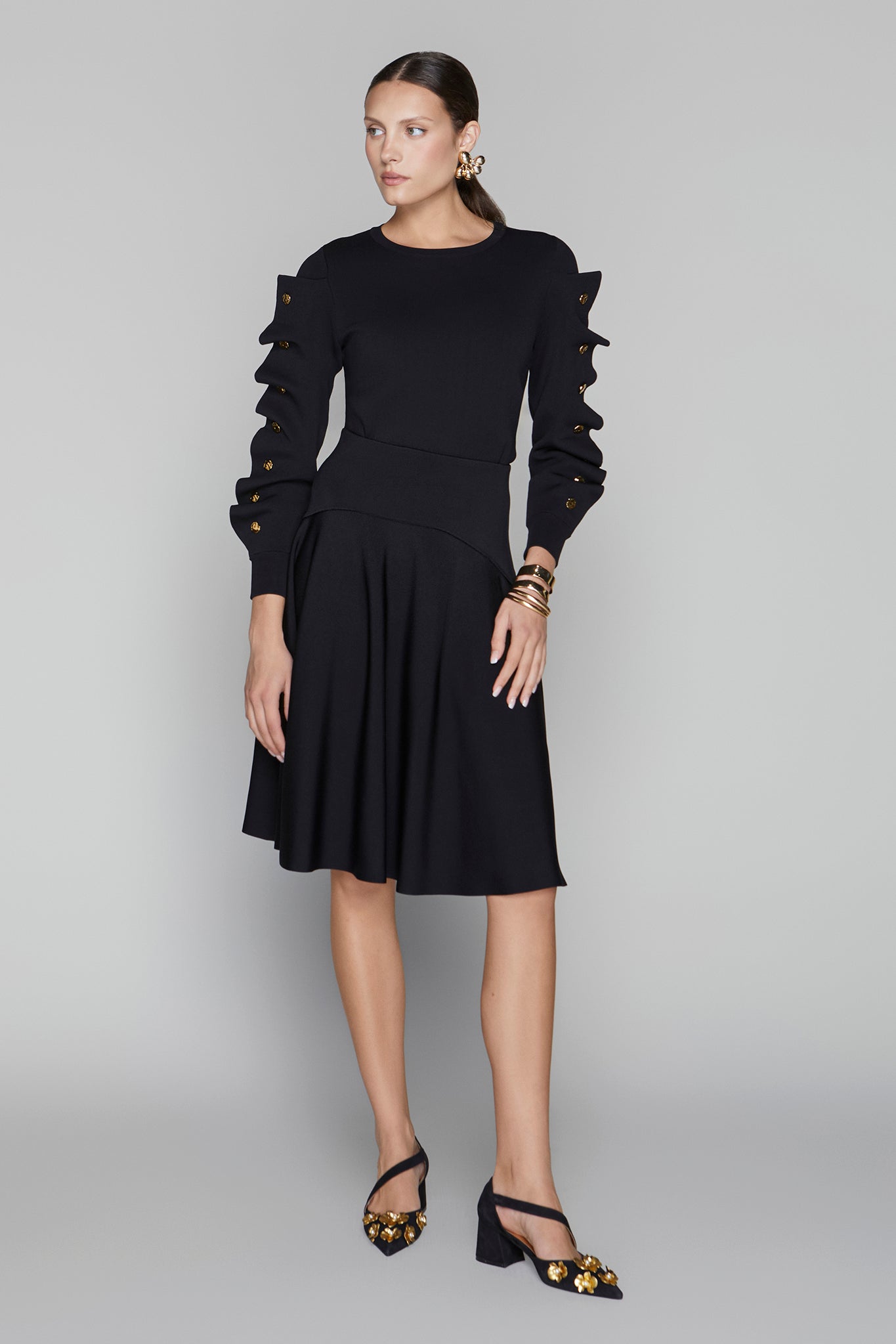 Woman wearing a black dress with ruffled sleeves on a gray background