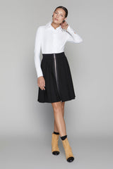 Woman wearing a white blouse and black skirt with a zipper on a gray background