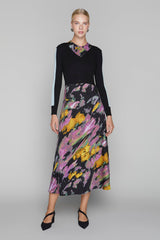 Woman wearing a black top and colorful skirt on a gray background