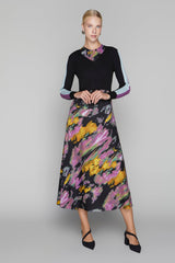 Woman wearing a black top and colorful skirt on a gray background