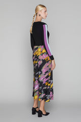 Woman wearing a black top with colorful abstract patterned skirt on a gray background