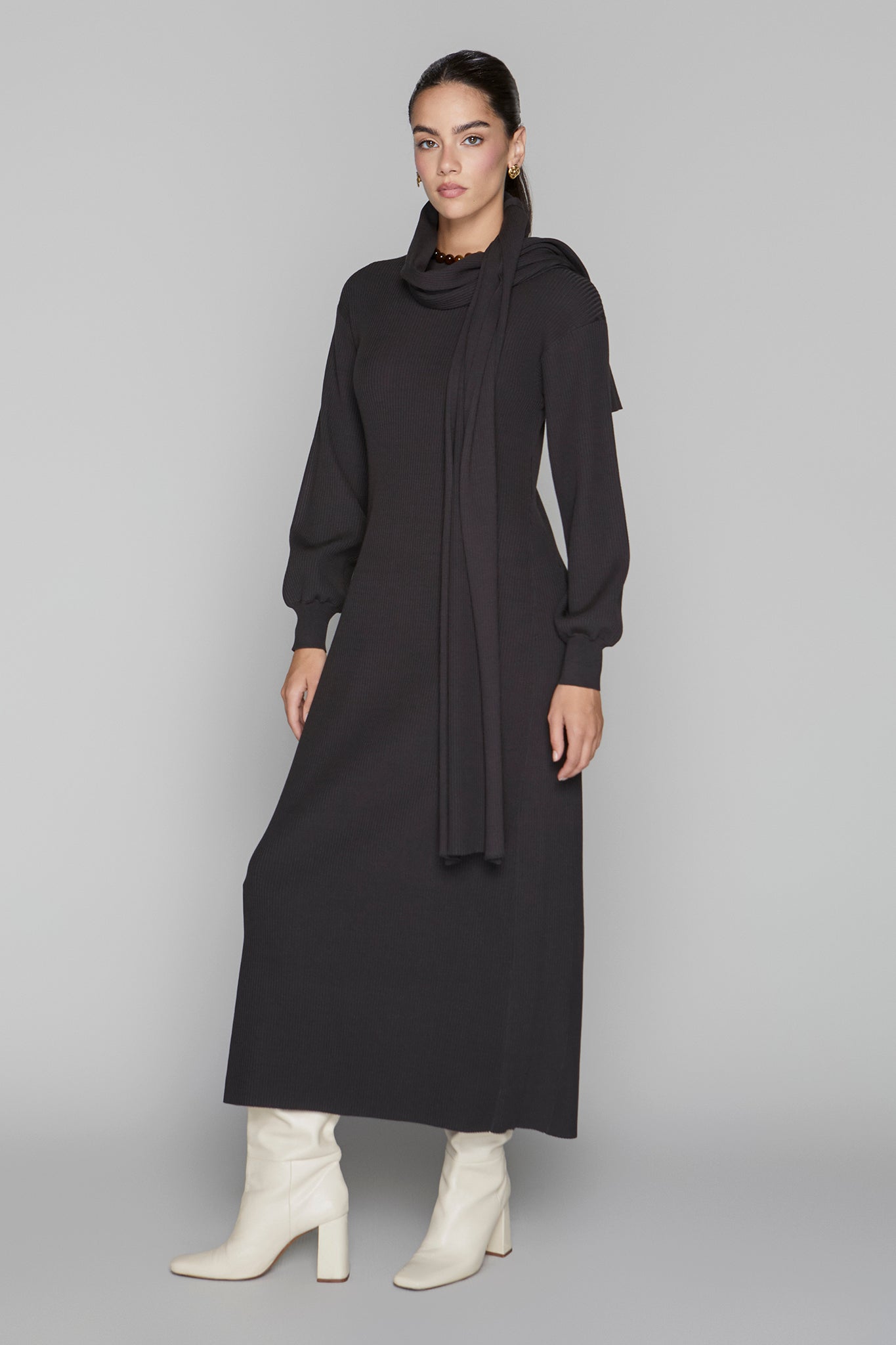 Woman wearing a long black dress with a plain background