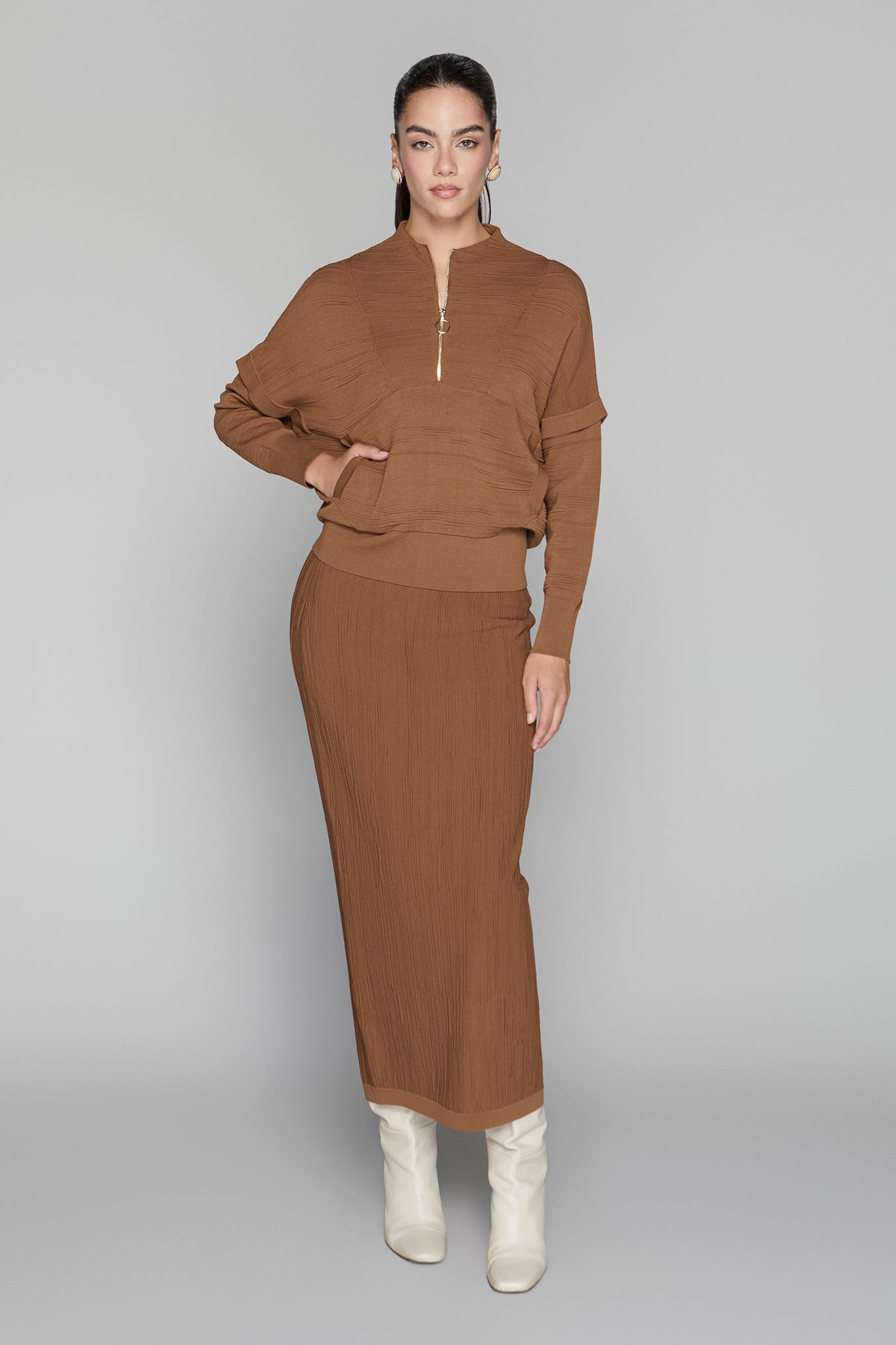 Woman wearing a brown outfit with a long skirt on a gray background