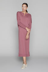 Woman wearing a long pink dress on a gray background