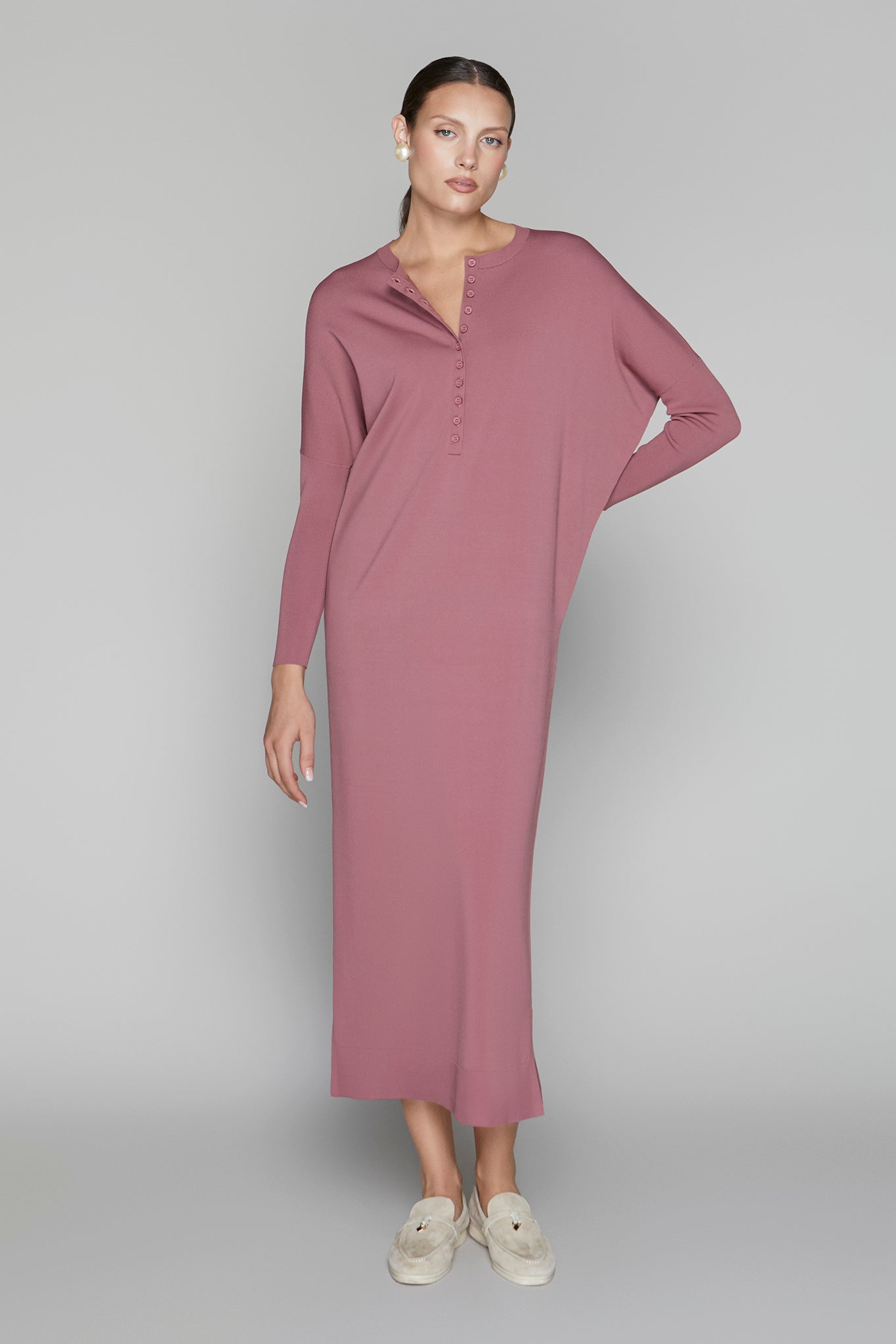 Woman wearing a long mauve dress on a gray background