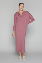 Woman wearing a long mauve dress on a gray background