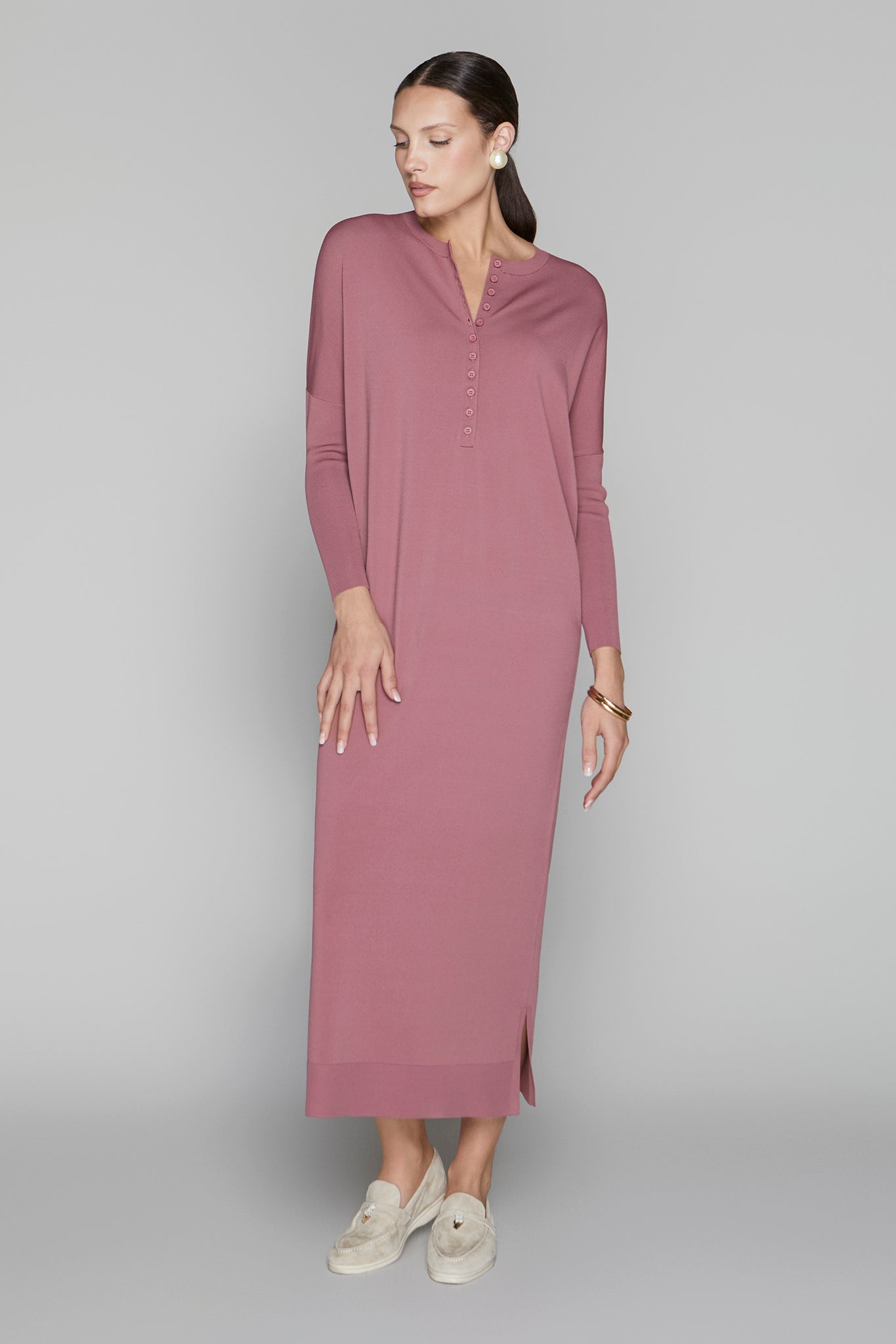 Woman wearing a long mauve dress on a gray background