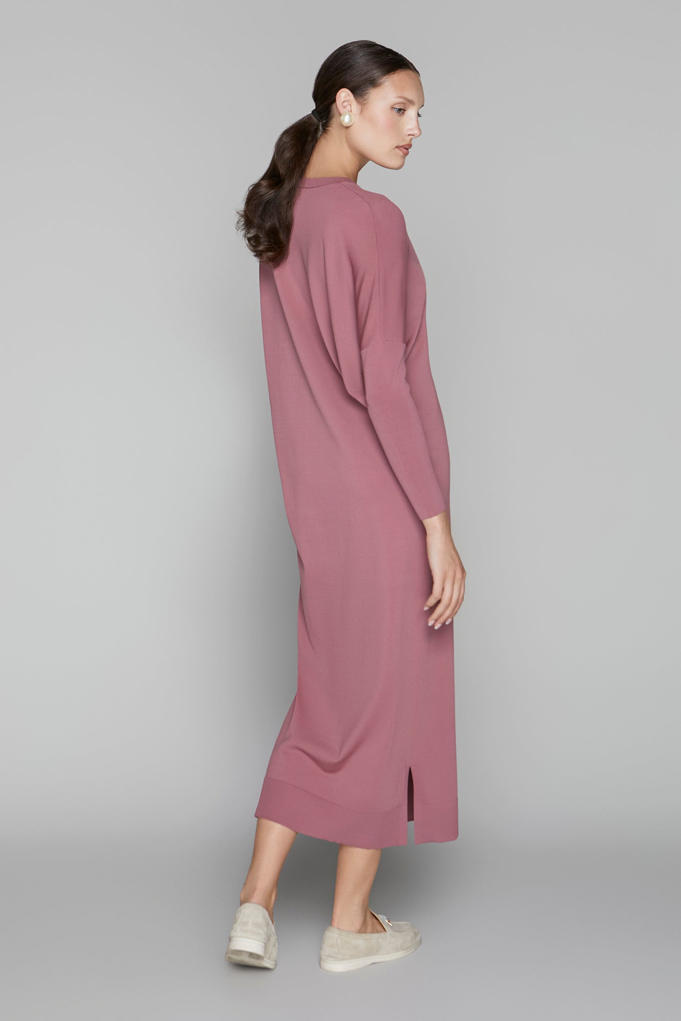Woman wearing a long mauve dress on a gray background